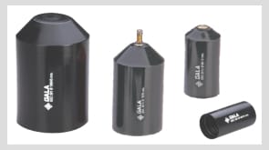 Four black moulded heat-shrink end caps of increasing diameter standing on a white ground, two of them fitted with a small brass relief valve in the domed top