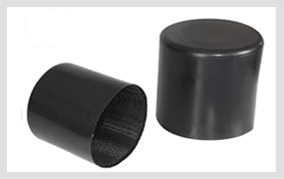 Two black heat-shrink pile caps photographed side by side: one tilted to show the textured adhesive lining inside its open bore, the other standing upright on its closed end.